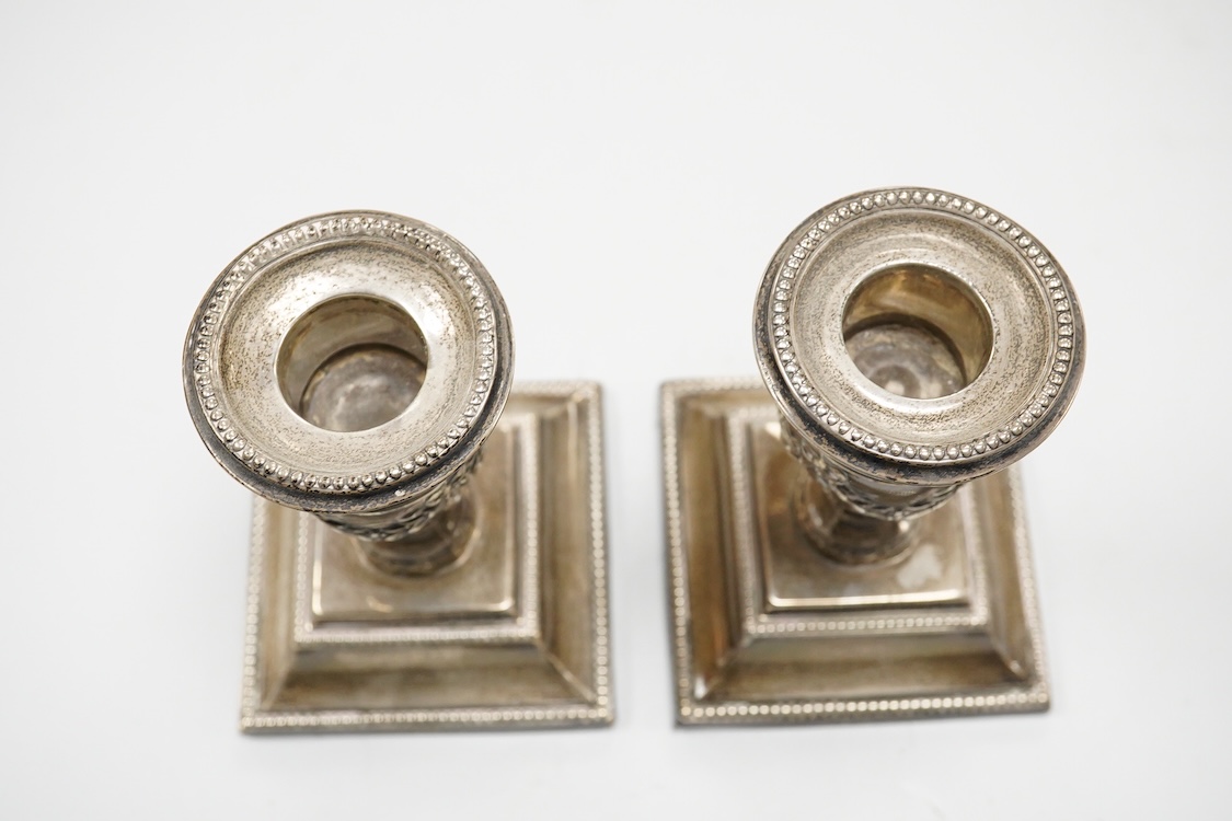 A pair of late Victorian silver mounted dwarf candlesticks, embossed with swags, on beaded bases, by Barker Brothers, Birmingham, 1899, height 11.5cm, weighted.